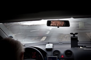 Picture of a Man Sitting in a Car in Distress as Seen in the Rearview Mirror.